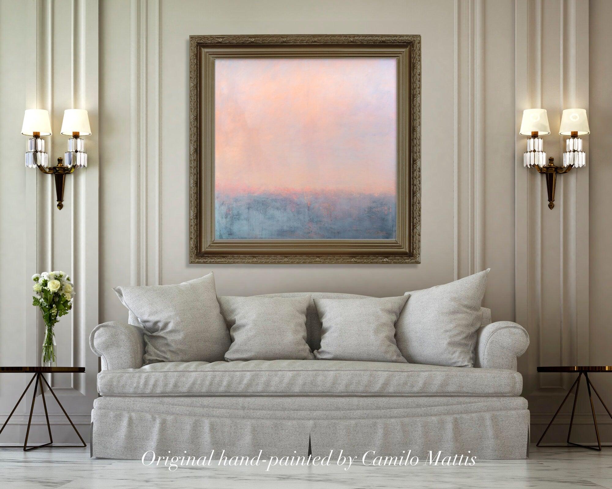 On a beige wall, there is a classic couch with an original abstract painting on canvas in peach and blue by Camilo Mattis